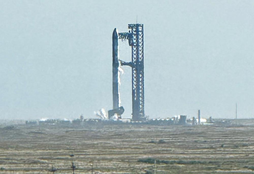 SpaceX Starship rising on a column of flame and exhaust at Starbase, seen from South Padre Island